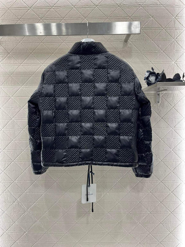 Black quilted jacket on a rack against a tiled wall