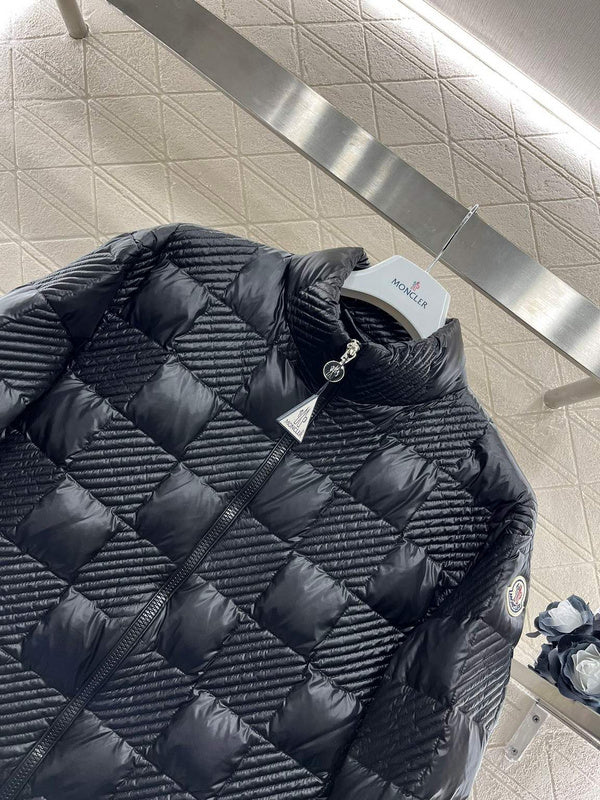 Black quilted jacket on a stand with a visible brand logo in an indoor setting.