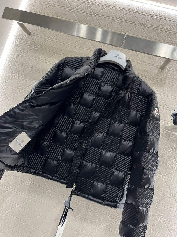 Black quilted jacket on a hanger with a brand tag in an indoor setting