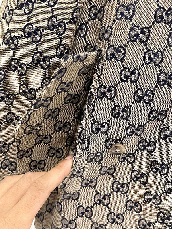 Close-up of a patterned fabric with a hand pointing to a button.
