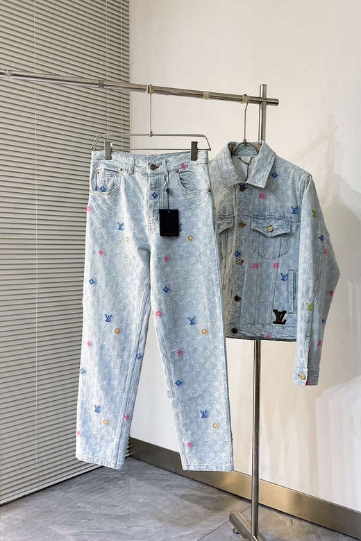 Denim jacket and pants with colorful embroidery on a metal rack against a white wall.
