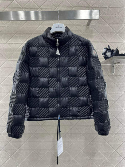 Black quilted jacket with brand tag on a tiled wall